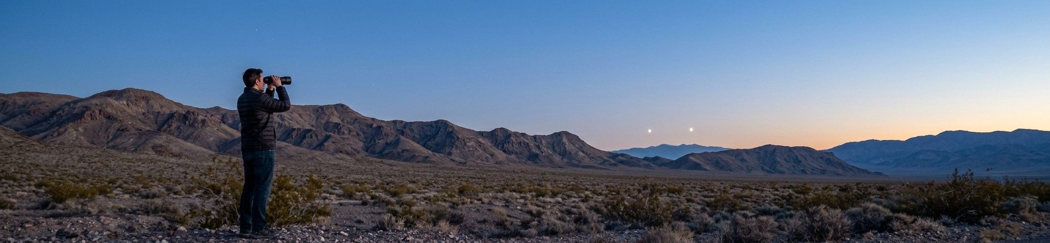 A lone observer scanning the dusk sky with binoculars toward two distant lights over a desert ridge
